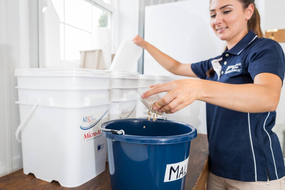 Woman measuring supplements into feed bucket